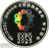 2025年日本国際博覧会 大阪・関西万博記念1000円銀貨・1,000円銀貨プルーフ 図案・表面:2025年日本国際博覧会ロゴマークと夢洲の万博会場 裏面:2025年日本国際博覧会ロゴマーク(虹色発色加工)旧新橋停車場の図柄 直径:40.00mm 品位:純銀99.9% 量目:31.1g 発行数:50,000枚・プルーフ・造幣局製額面:千円