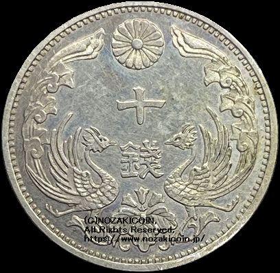 八咫烏銀貨は初めて一般公募による図案が採用されました。  表中央の価額の左右に鳳凰、裏面日章の真ん中に八咫烏が配されています。  銀価格高騰の為、流通しませんでした。  八咫烏10銭銀貨は直径16.06mm 品位は銀720 / 銅280 量目は1.50gです。  大正8年（1919）鑑定書付。